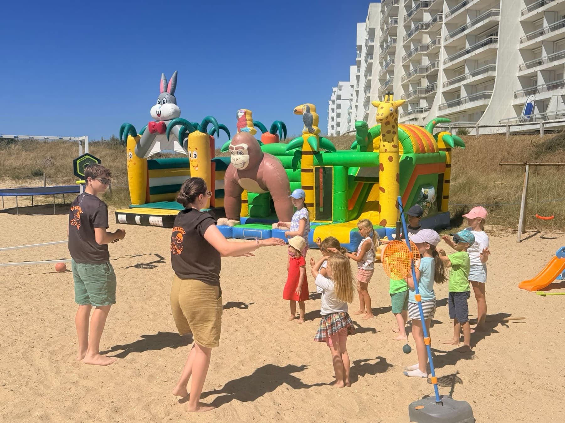 Animation sur la plage d'un camping, au pied des structures gonflables.