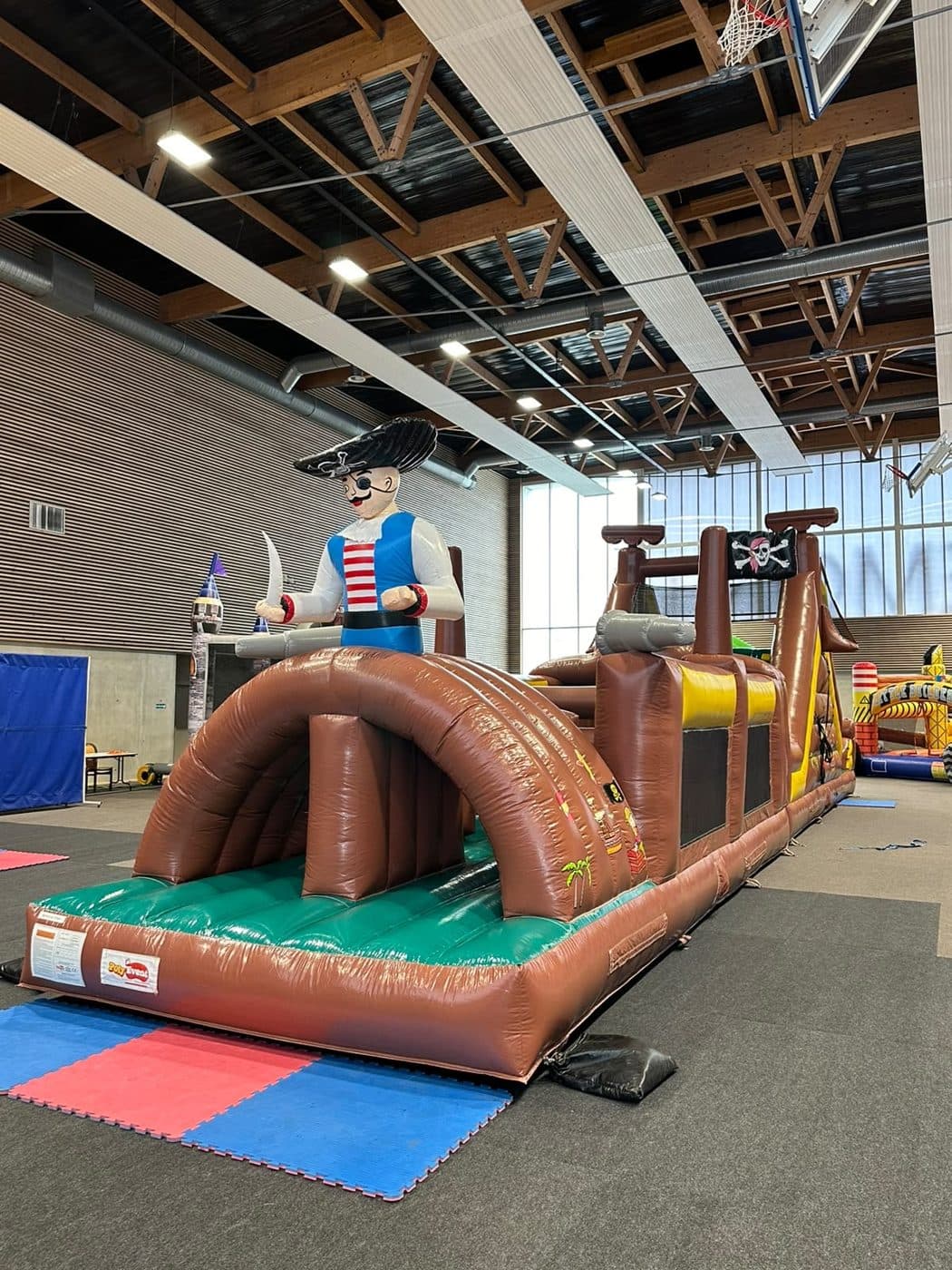 Parcours d'obstacles gonflable sur le thème des pirates, installé en gymnase.