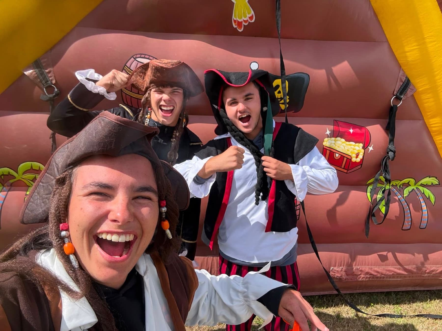 Animatrices déguisées en pirates, hilares, devant un château gonflable.